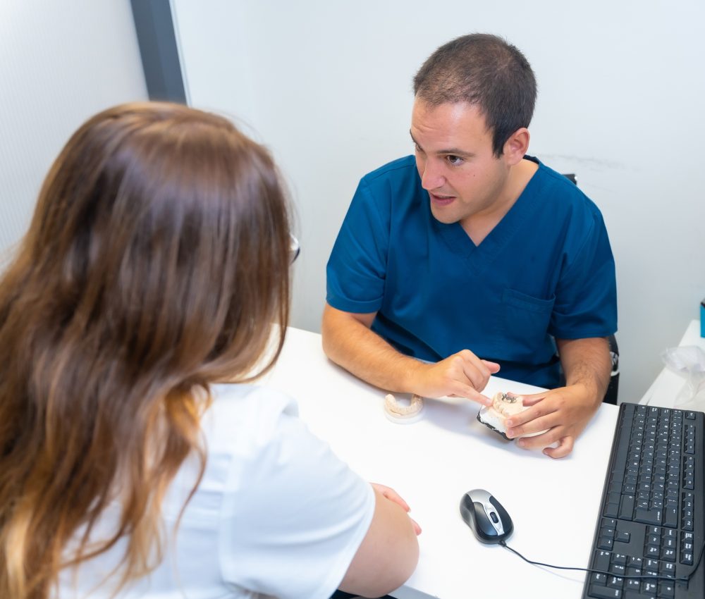 Dental clinic, dentist explaining to a client the teeth to be implanted in a model