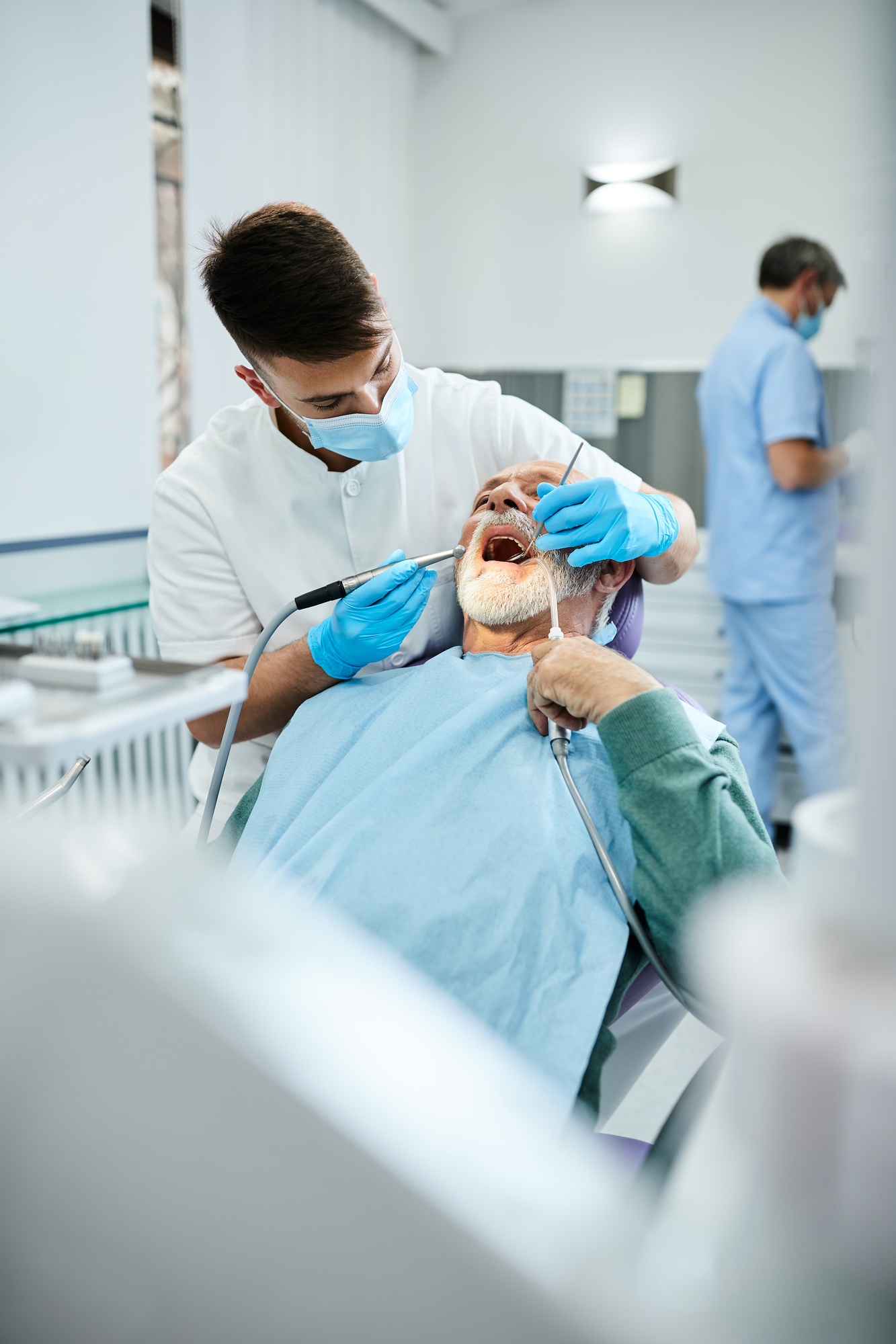 Young dentist examining teeth of senior patient at dental clinic.